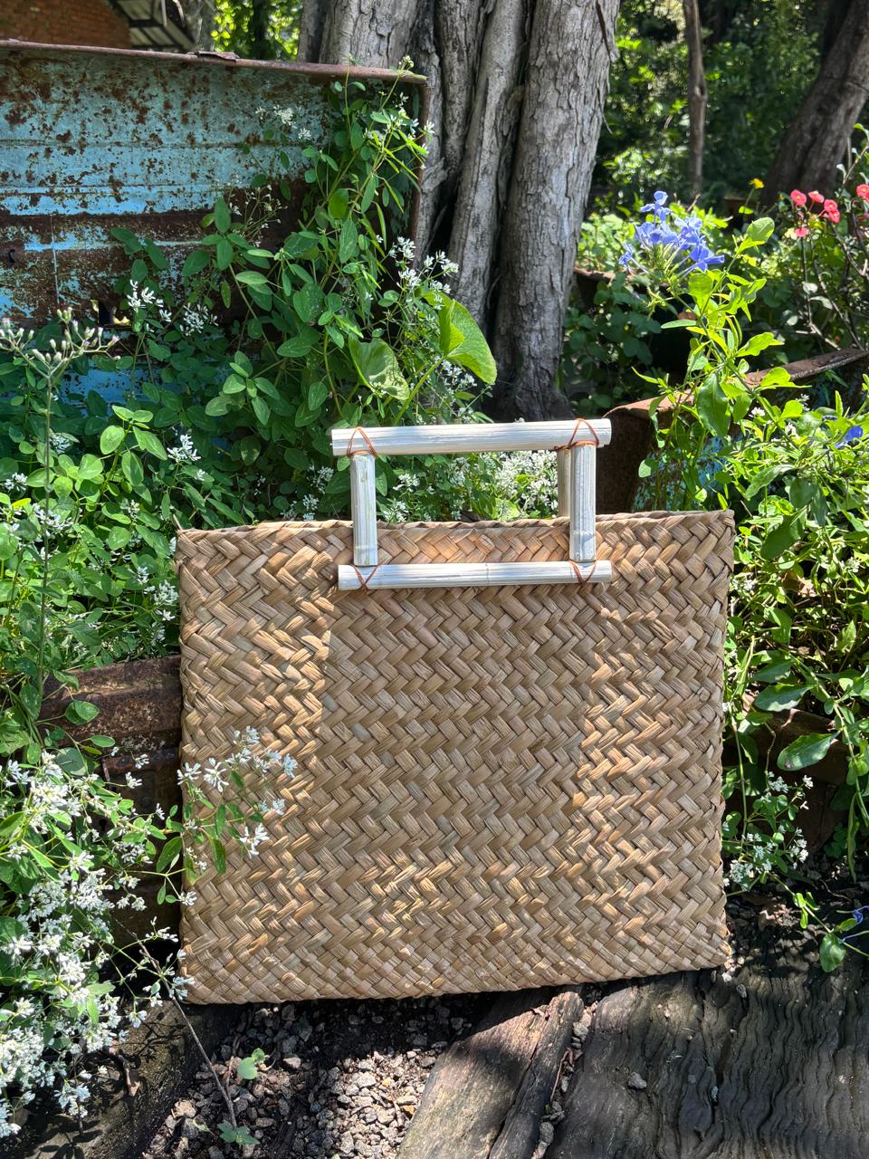 A handwoven straw bag with a rattan handle and tassel at Hambu Café's gallery shop